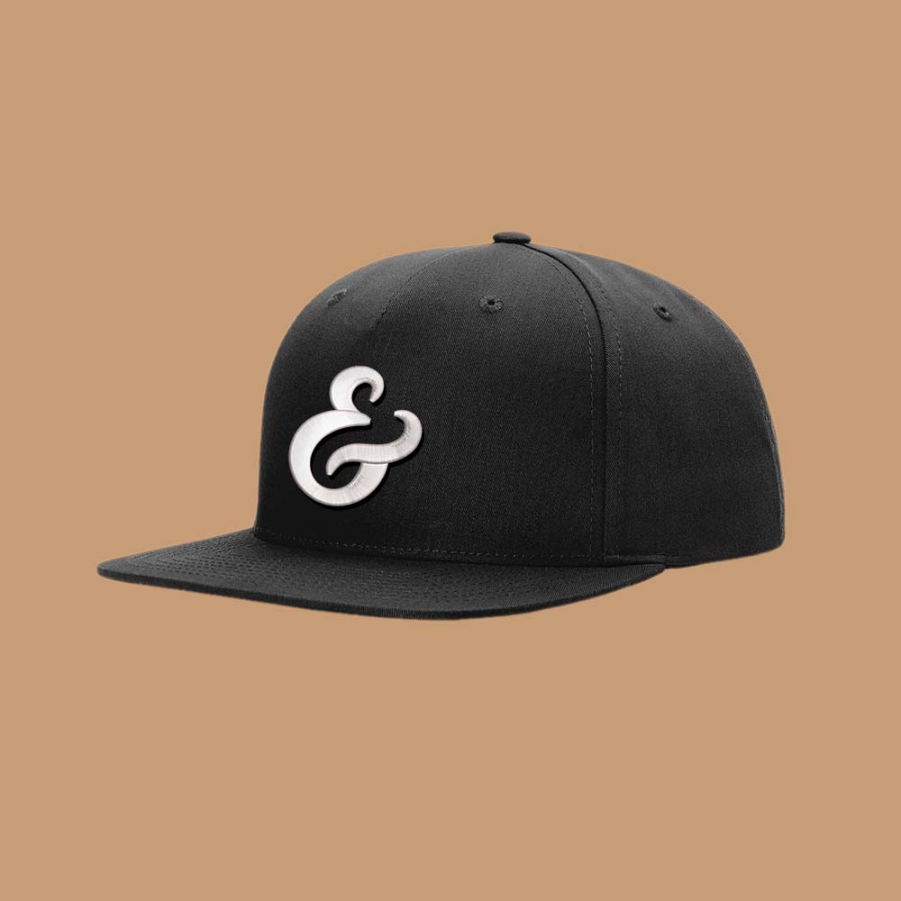 Black snapback hat with a white ampersand embroidered on the front